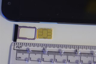 一张 nano SIM 卡和它的卡托，旁边有一把标尺