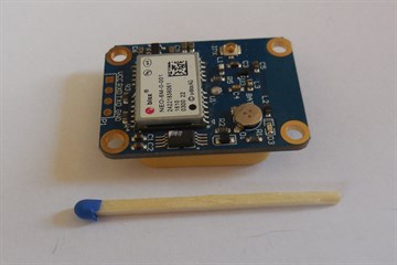 一块 u-blox NEO-M8N GNSS 模块板，旁边有一根火柴作比例